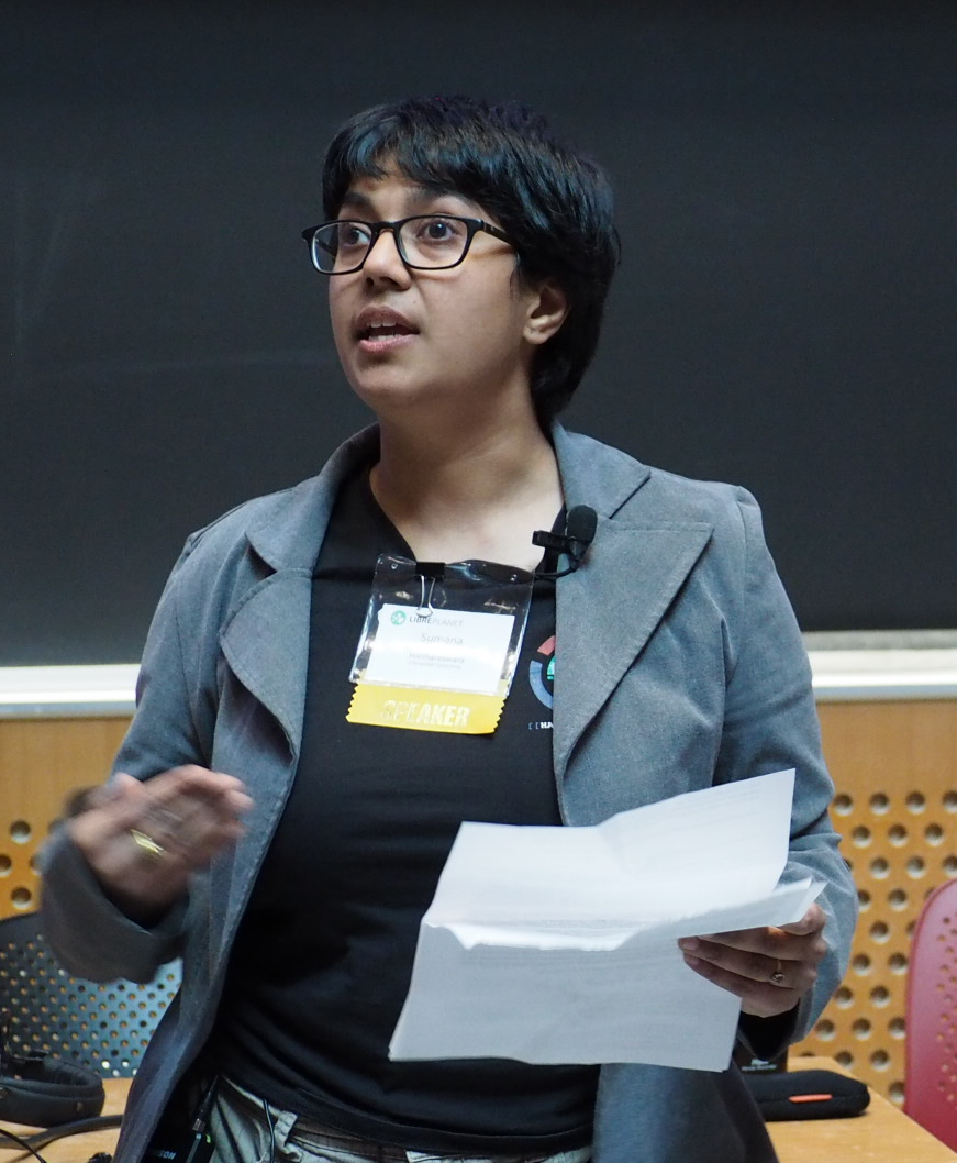 Photo of Sumana Harihareswara speaking at LibrePlanet
2016. She is in front of a black board at the front of a lecture
hall, gesturing as she speaks.