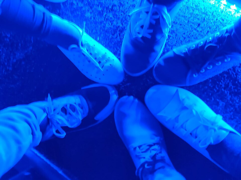 A group of sneakered feet in a circle, toes in'