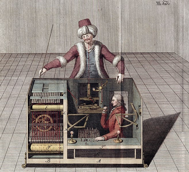 Image of a person inside a box with various levers, as a person stands above the box, seemingly playing chess.