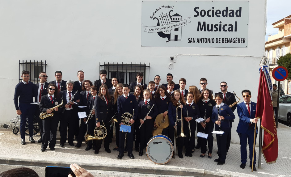Students and teachers of the Sociedad Musical de San Antonio de Benagéber, a music school in Spain, pose with their instruments and flags.