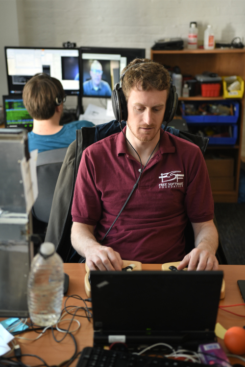 Photo of the FSF tech team coordinating with remote conference speakers