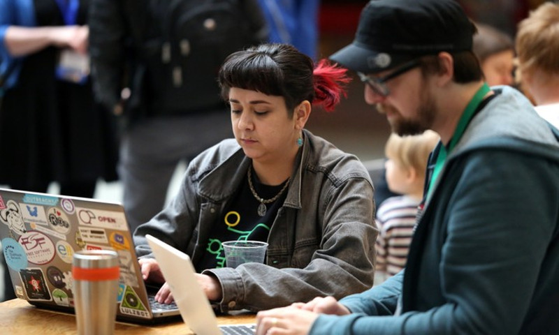 [ 2 people working on a computer at libreplanet. ]