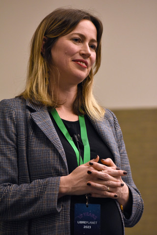 An image of Erin Rose Glass standing with hands folded at the chest.