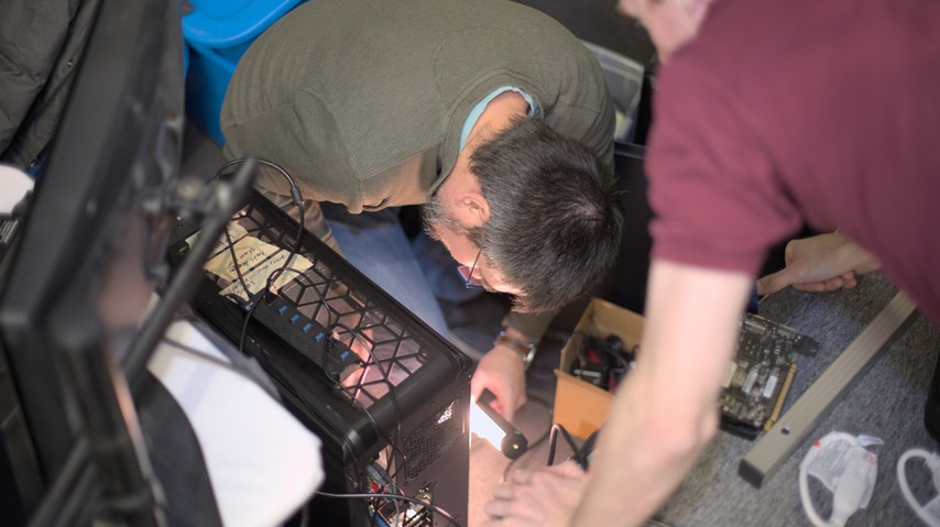 A photo of Rubén Rodríguez Pérez and Ian Kelling, swapping out video cards during LibrePlanet 2023.